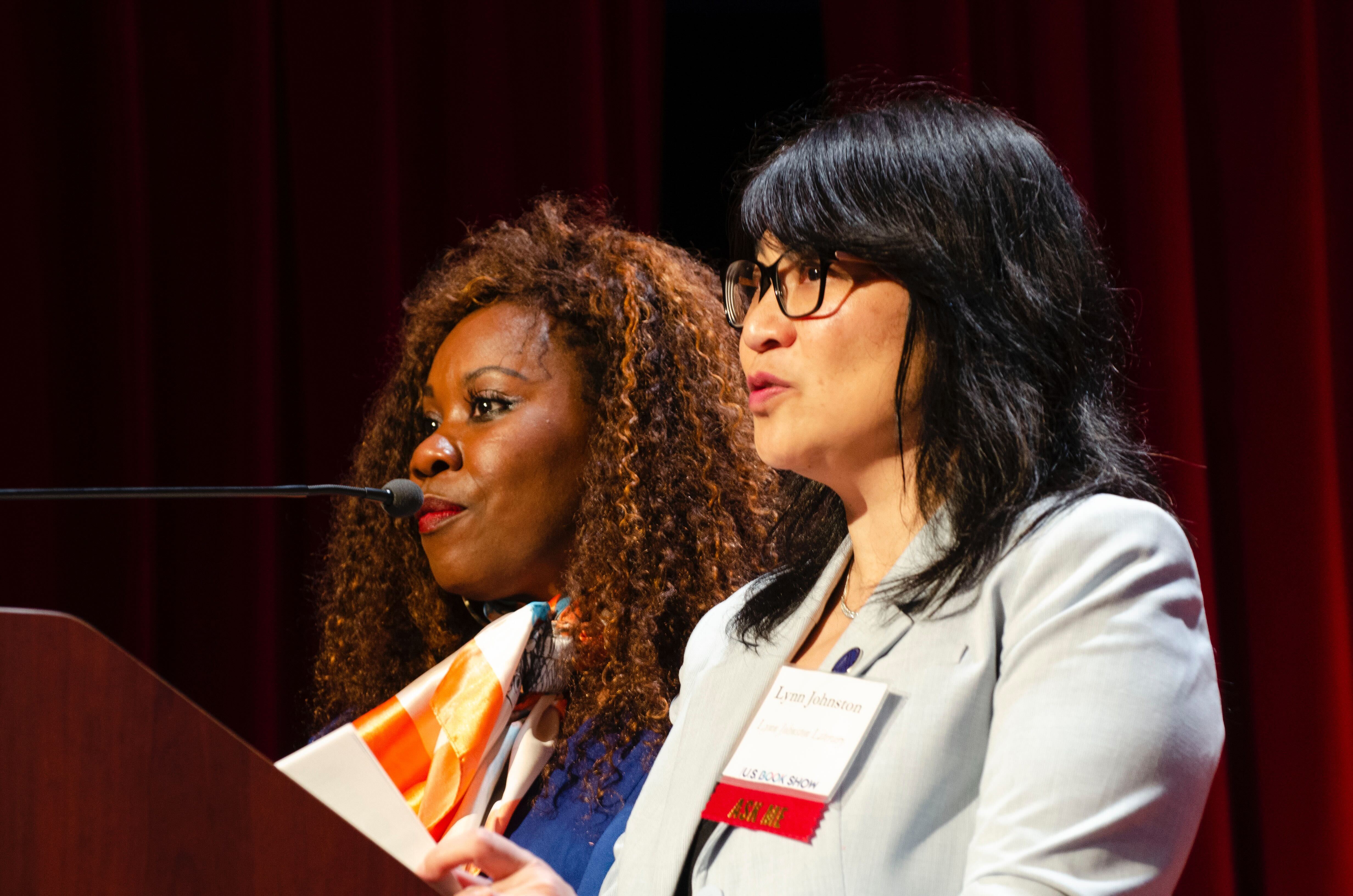 Regina Brooks and Lynn Johnston at a podium with a mic